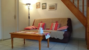 Een gezellige woonkamer met een bank, een houten salontafel en een vloerlamp.