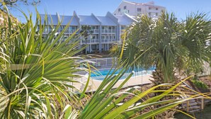 Ein Hotel mit Pool, umgeben von Palmen und wolkenlosem, blauem Himmel.