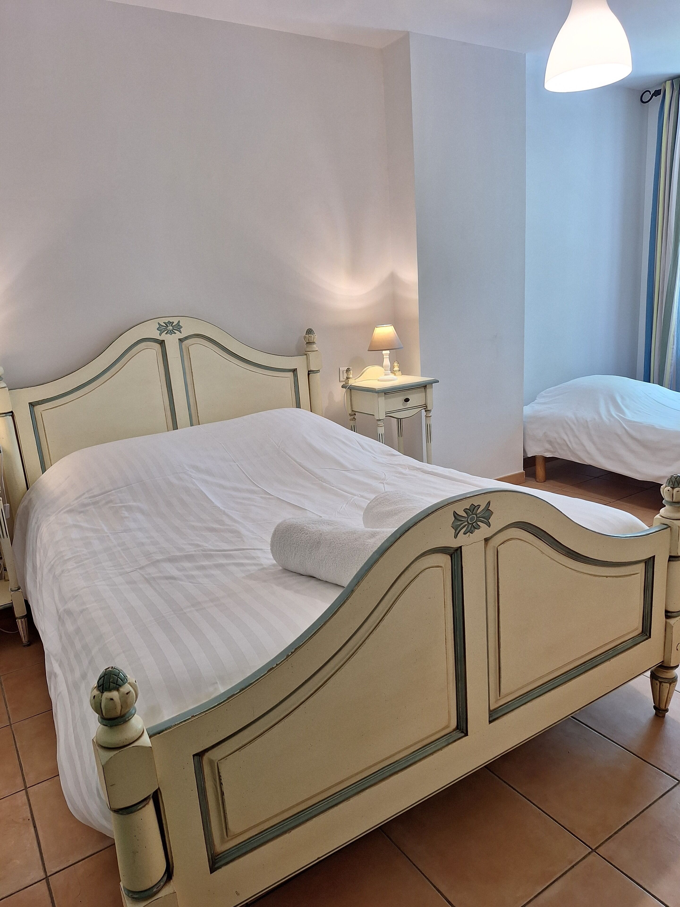 Een keurig opgemaakt bed met een witte deken en een opgevouwen handdoek.