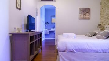 Hotelkamer met een bed, televisie, kledingkast, badkamer zichtbaar door een boog, en een schilderij aan de muur.