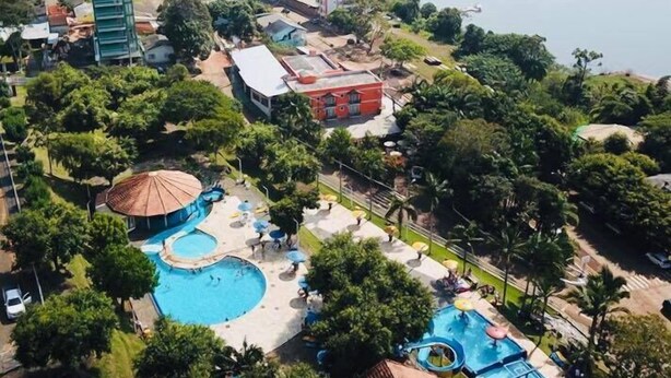 An aerial view of a resort with a large swimming pool, multiple buildings, and a lake in the background. - Thermas Classic Hotel (Marcelino Ramos)