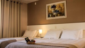 A hotel room with two beds, a painting on the wall, a nightstand with a lamp, and a basket of toiletries on the bed. - Thermas Classic Hotel (Marcelino Ramos)