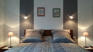 A neatly made bed with a patterned bedspread and two pillows, flanked by bedside lamps on either side. - Detached house in a quiet private courtyard in the heart of Bergheim (Bergheim)