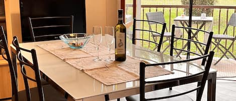 A dining area with a table set for two, a bottle of wine, and a painting on the wall.
