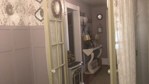 A room with a wooden floor, a fireplace, and a door leading to another room.