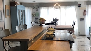 A dining area with a long wooden table, chairs, a chandelier, and a cabinet with glass doors.