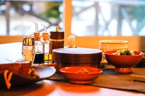 Una mesa con diferentes vasos, una vela y un cuenco de fruta.