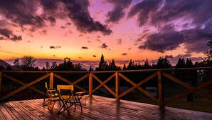 A wooden deck with two chairs facing a sunset view. - Numajiri kogen lodge (Inawashiro)