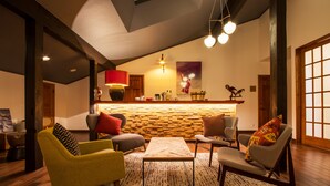 A modern living room with a wooden accent wall, a central coffee table, and seating with colorful cushions. - Numajiri kogen lodge (Inawashiro)