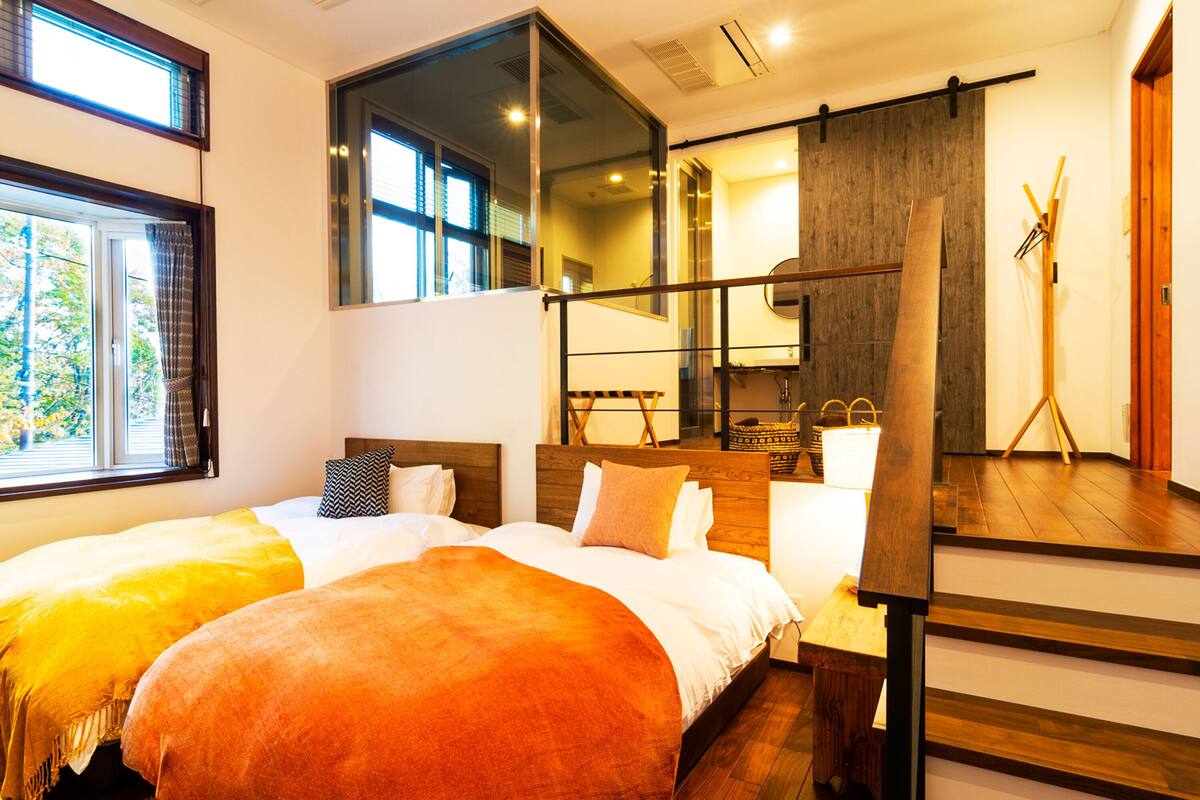 A hotel room with two beds, a large mirror, and a wooden staircase.