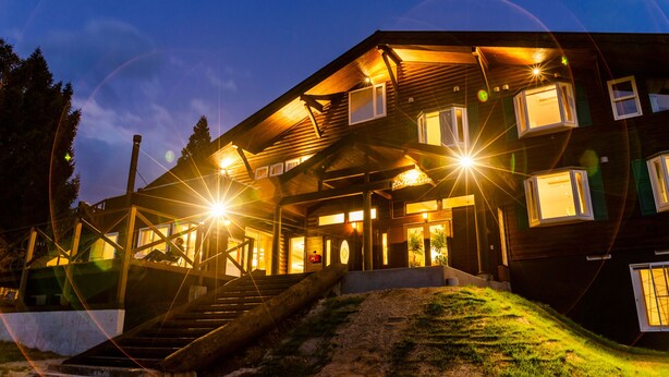 A two-story wooden lodge with a covered porch and multiple windows. - Numajiri kogen lodge (Inawashiro)