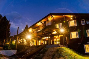 Un chalet en bois à deux étages, doté d’un porche couvert et de nombreuses fenêtres.