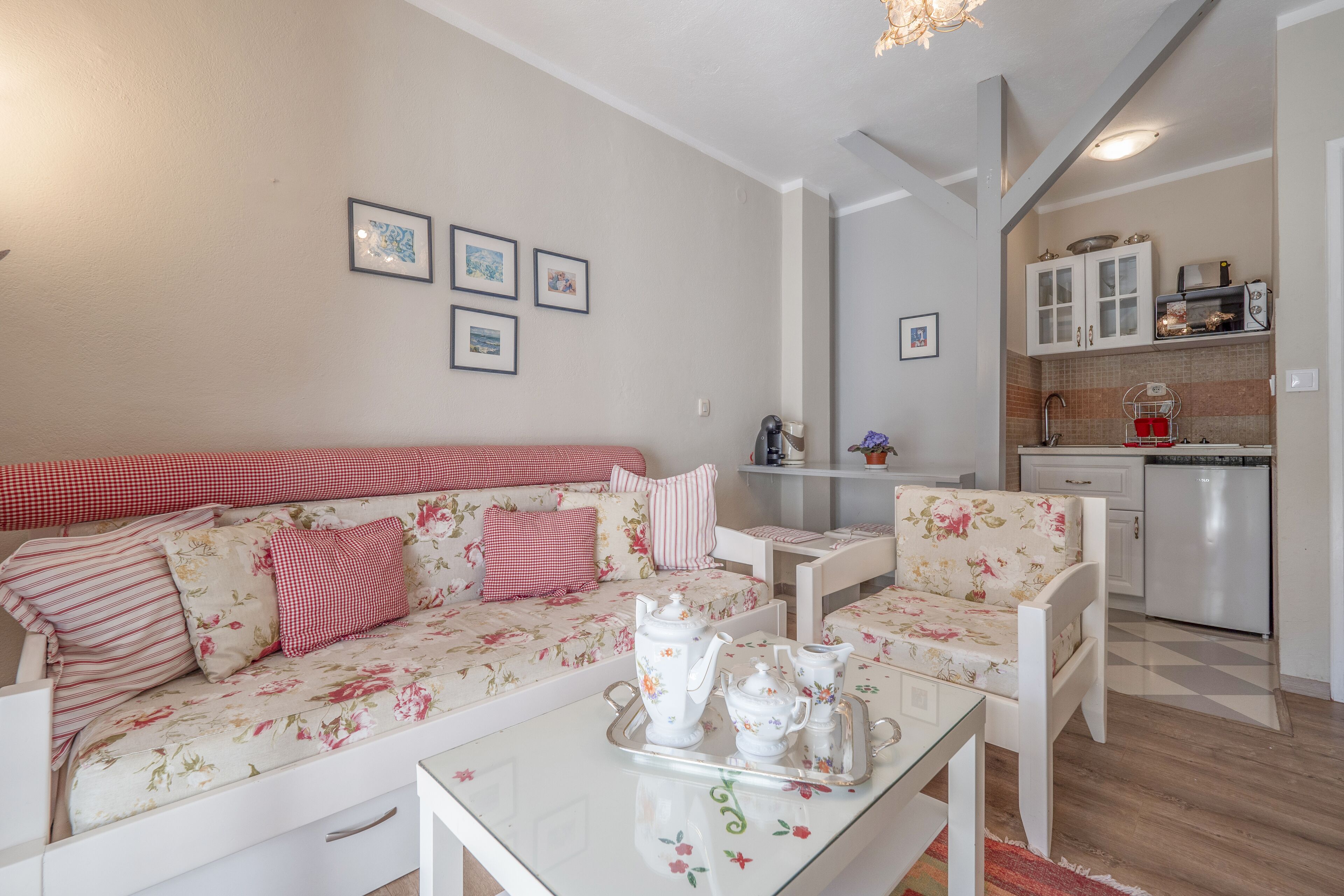 A cozy living room with a sofa, chairs, a coffee table, and a kitchen area with cabinets and appliances.