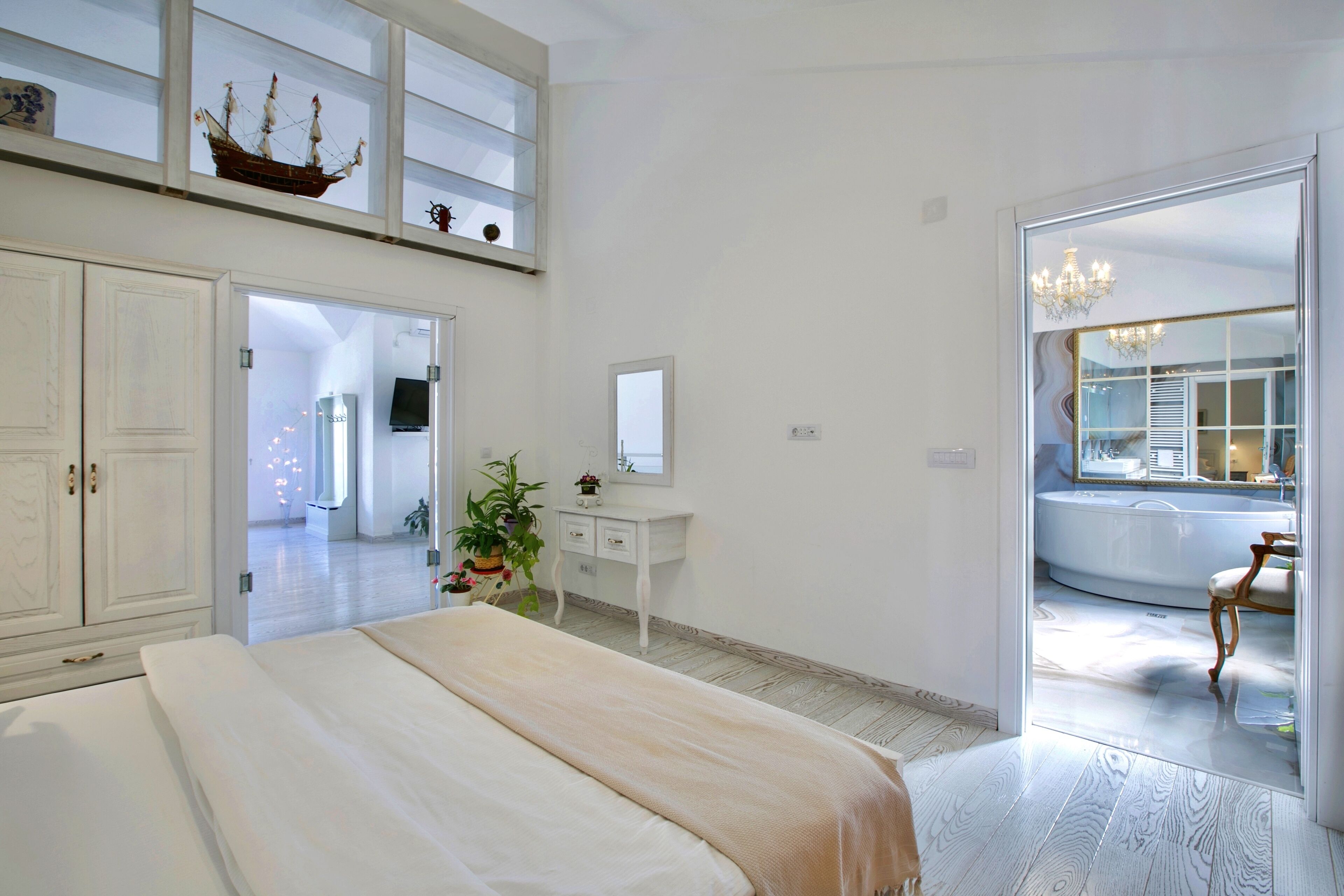 Une chambre à coucher avec un lit, une commode, un miroir et une plante en pot.