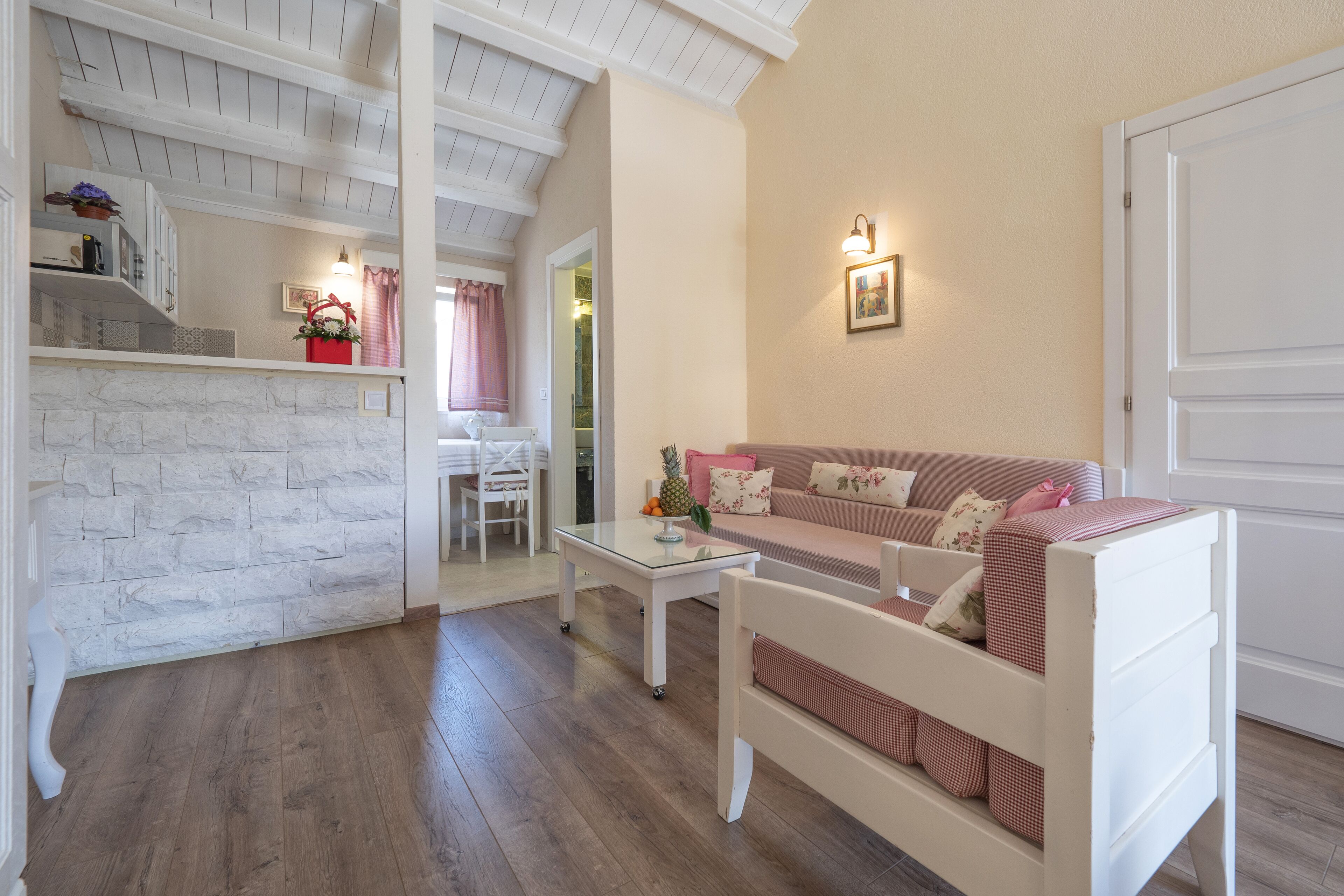Un'accogliente zona living con un divano bianco, un tavolino da caffè e un mobiletto bianco decorato con oggetti vari.