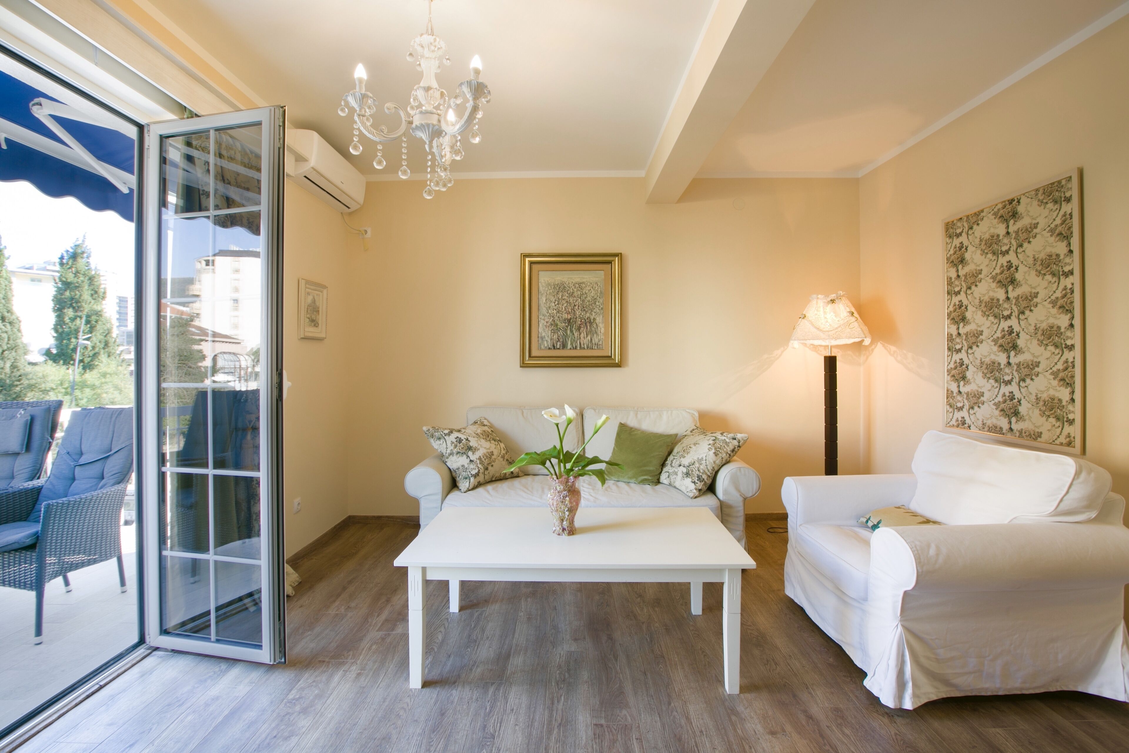 Una sala de estar con un sofá blanco, un sillón blanco, una mesa de centro y una araña.