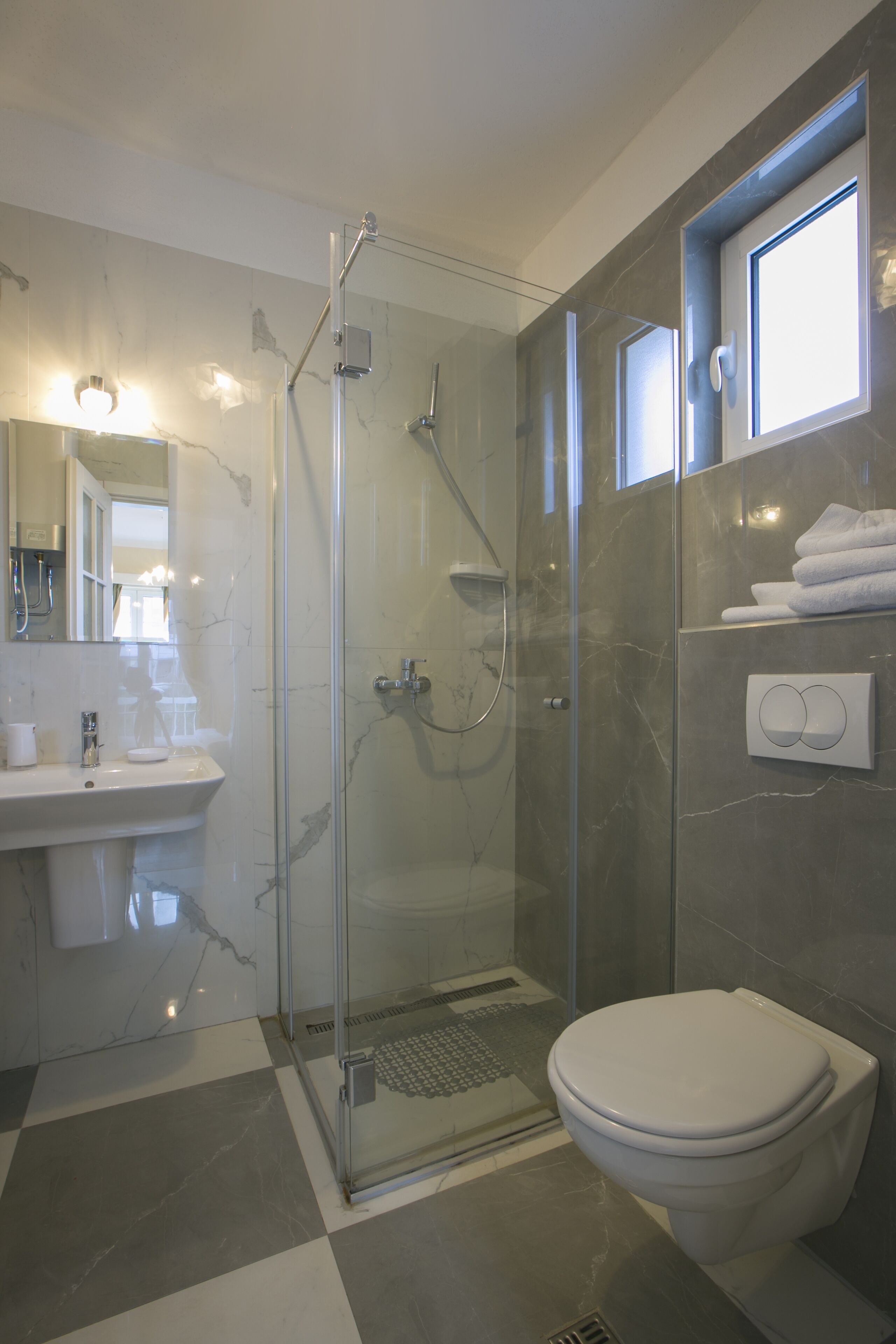 Un baño moderno con ducha envuelta en vidrio, un lavamanos blanco y un inodoro.