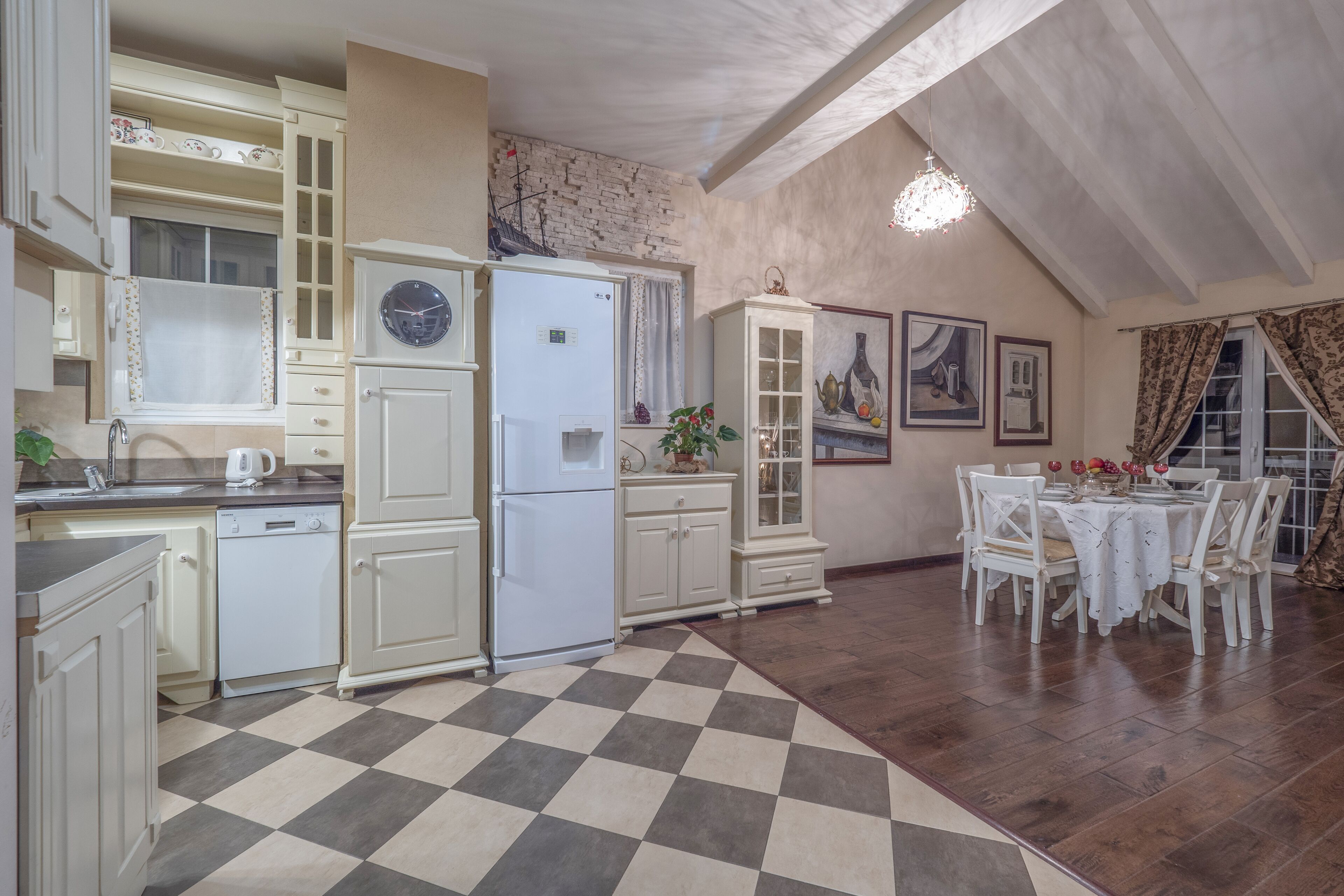 A kitchen with white cabinets, a refrigerator, and a dining area with a table and chairs.