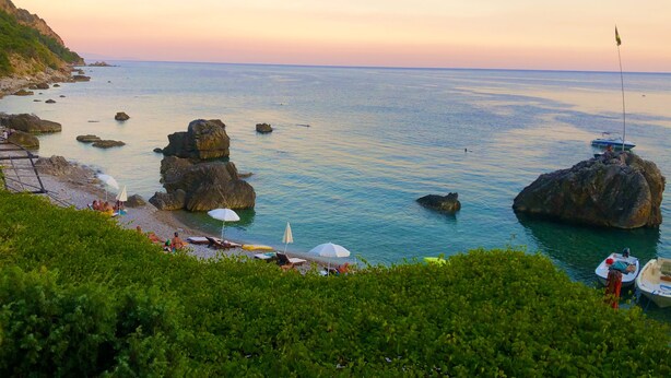 A coastal view with rocky formations, clear water, and a few boats. - Marinero Apartments (Budva)