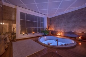 Un baño moderno con una bañera grande, una ventana con vistas y una pared de piedra.