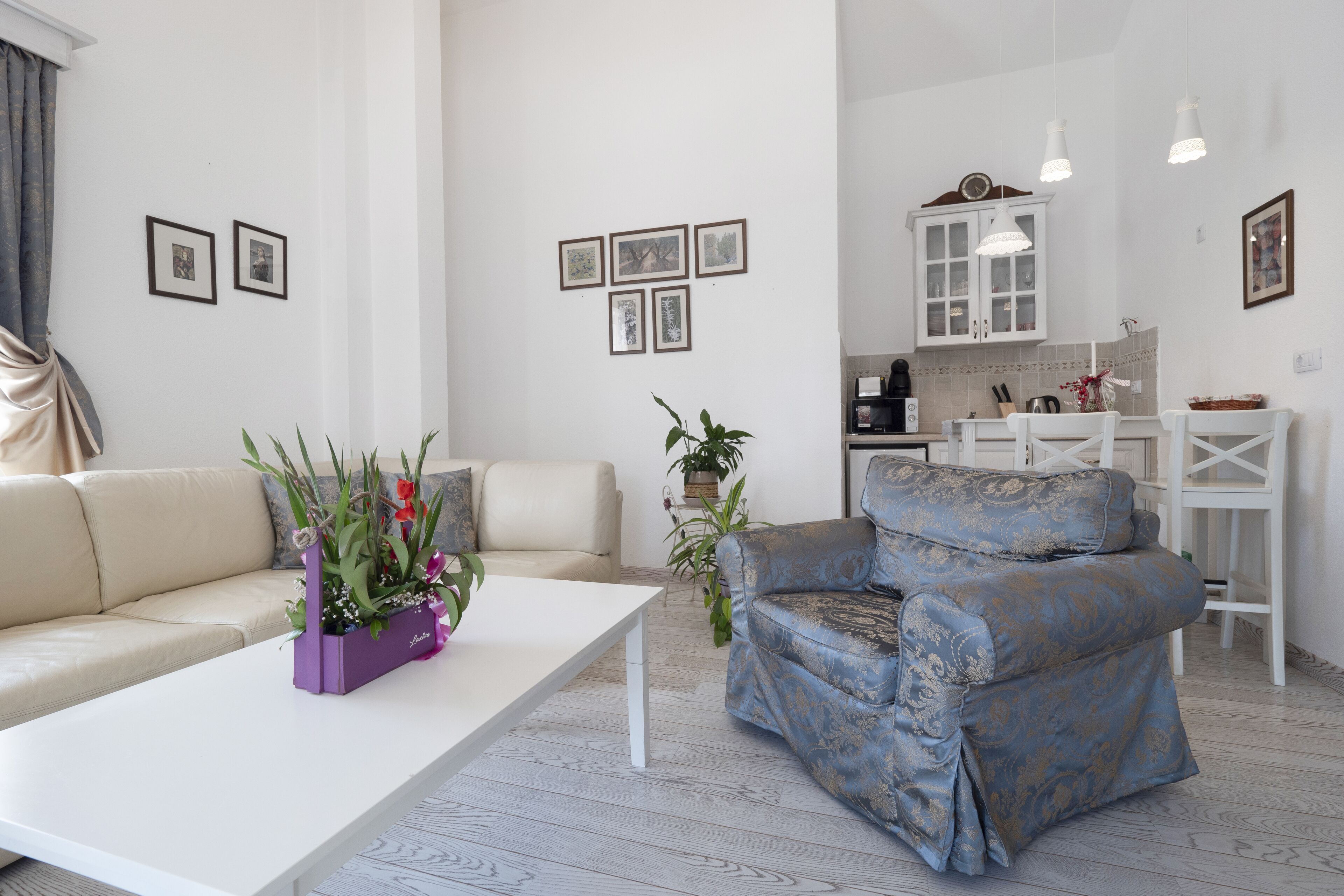 A modern living room with a sofa, armchair, and a coffee table with a purple vase.