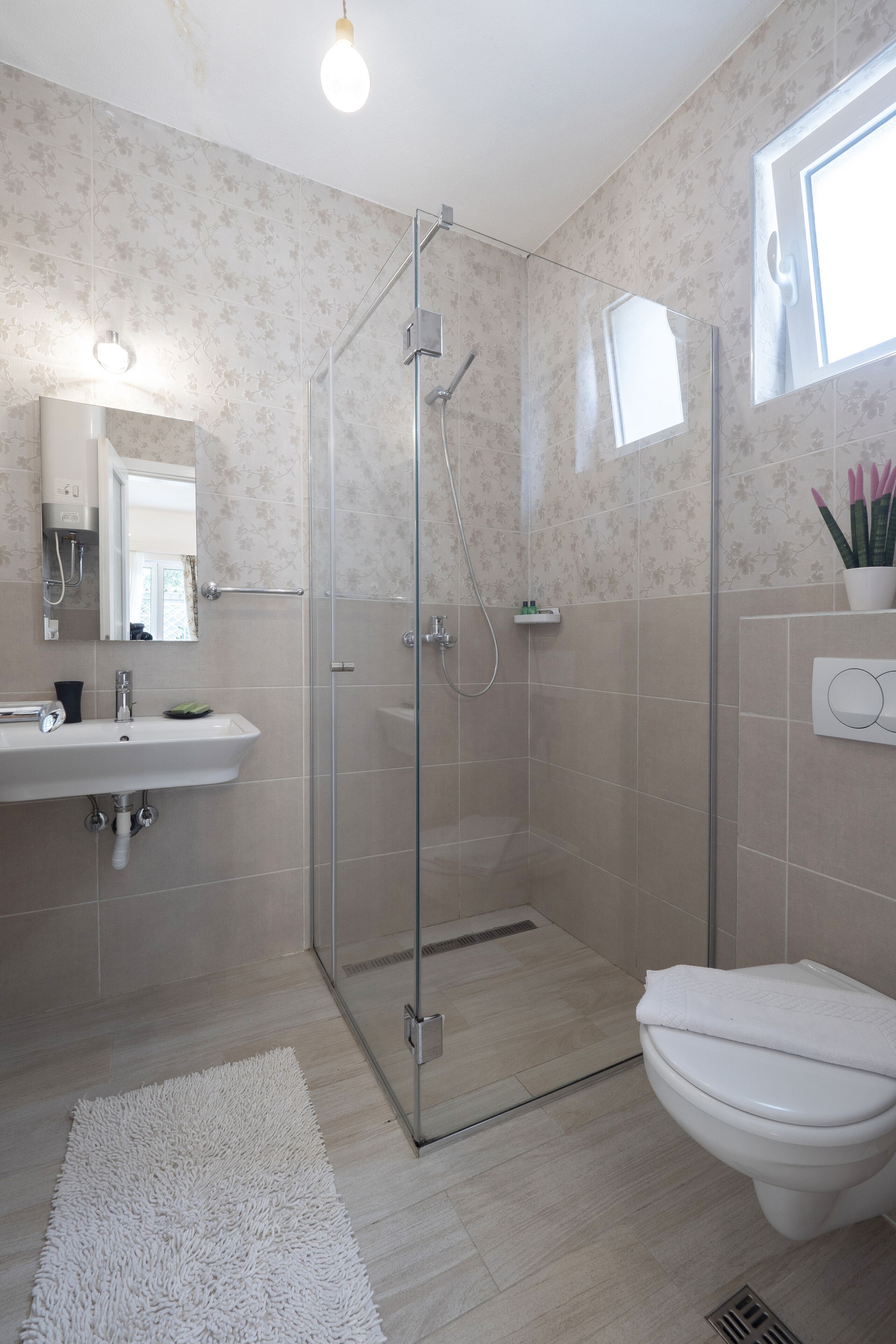 A modern bathroom with a glass-enclosed shower, a white sink, and a toilet.