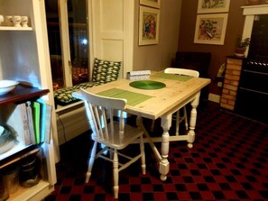 Ein Essbereich mit Holztisch und Stühlen, einem gemusterten Boden und einem Bücherregal mit Büchern und Dekoration.