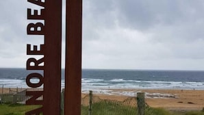 Un letrero que dice "FALMORE BEACH" con vista a la playa y el océano al fondo.