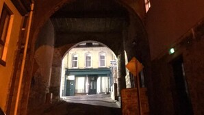 Un pasaje arqueado entre edificios, con un escaparate visible al final.
