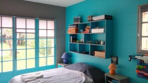 A bedroom with a bed, a shelf unit, a window, and a door. - The waterfall balcony (Trans-en-Provence)