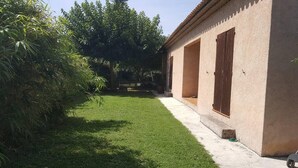 A residential property with a well-maintained lawn, a concrete pathway, and a building with a beige facade and wooden shutters. - The waterfall balcony (Trans-en-Provence)