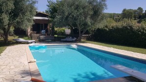 A rectangular swimming pool with a stone tiled deck, surrounded by trees and a wooden fence. - The waterfall balcony (Trans-en-Provence)