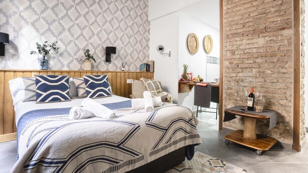 Ein modernes Schlafzimmer mit Bett, Nachttischen, einem Schreibtisch und einer Ziegelwand.