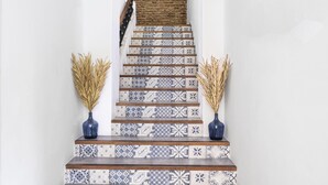 Eine Treppe mit gemusterten Fliesen und zwei Vasen mit Trockenpflanzen.