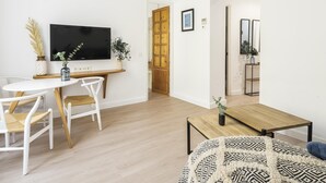 A modern living room with a TV, a dining table, and a sofa.