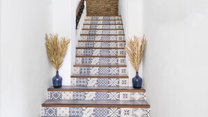 A staircase with patterned tiles and two vases of dried plants.