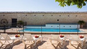 Una piscina con sillas de descanso y un muro de piedra.