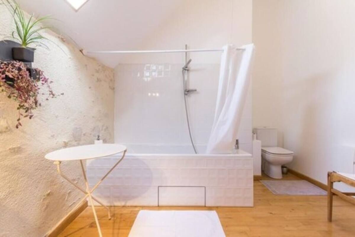 Un baño con ducha, inodoro y una mesita.
