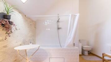 Une salle de bain avec une douche, des toilettes et une petite table.