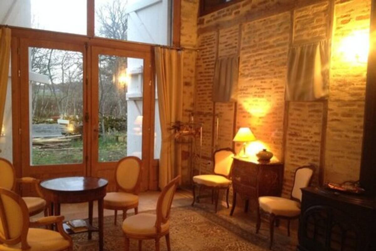 Una habitación acogedora con un ventanal grande, una mesa redonda y varias sillas.