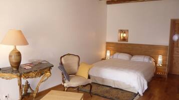 A bedroom with a bed, a chair, a small table, and a lamp.