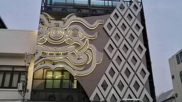 A modern building with a unique facade featuring geometric patterns and a large illuminated design.