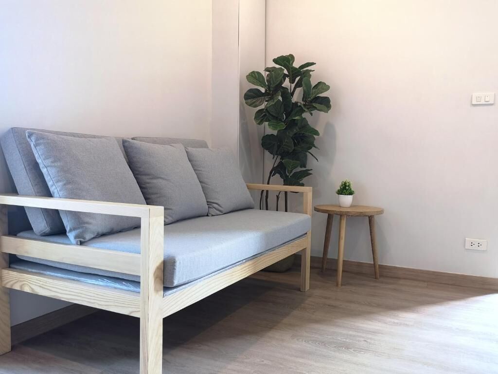 Ein schlicht eingerichteter Raum mit einer Holzsofa, einem kleinen runden Tisch und einem Blumentopf.