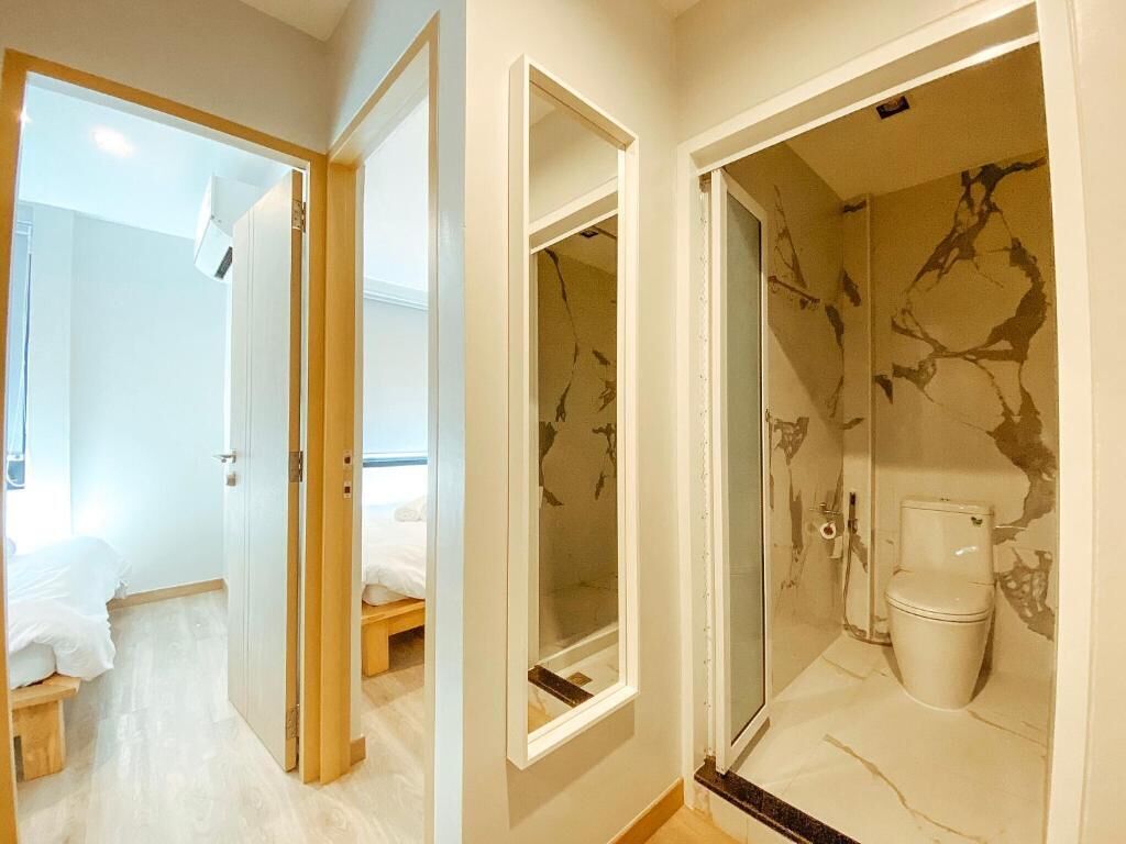 A hotel room with a bed, a small table, and a bathroom with a toilet and shower.