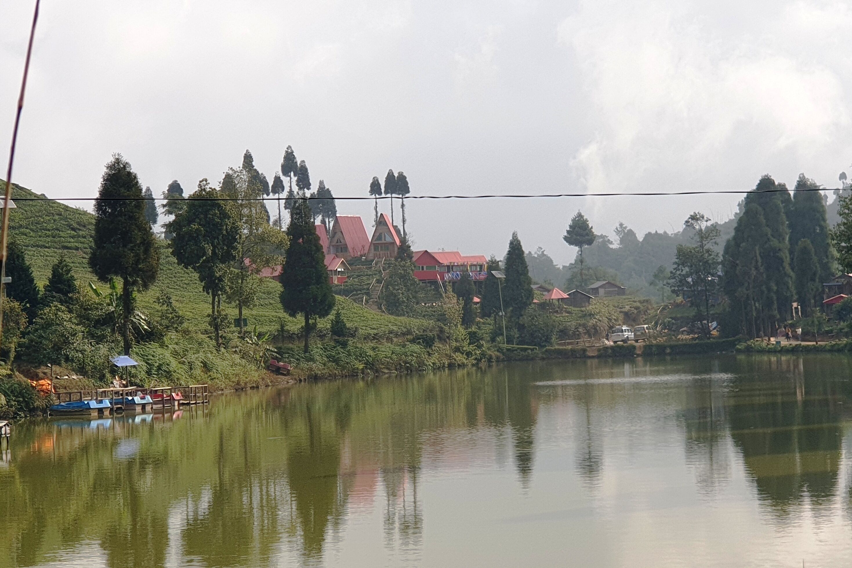 Un lago tranquilo con barcos, rodeado de exuberante vegetación y edificios tradicionales.