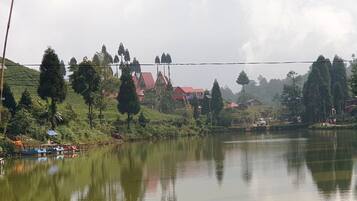 Un lago tranquilo con barcos, rodeado de exuberante vegetación y edificios tradicionales.