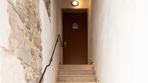 A staircase with stone walls, a handrail, and a door at the top.