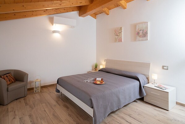 Une chambre à coucher avec un lit, des tables de chevet, une chaise et un plafond en bois.