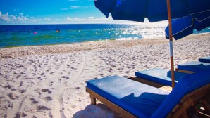 A beach with a blue umbrella and lounge chairs. - 4 Free Beach Chairs & 2 Umbrellas, Updated Beach-Front Condo, Large Balcony! (Panama City Beach)