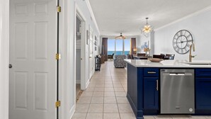 A modern kitchen with a built-in dishwasher, a large island, and a view to the outside. - 4 Free Beach Chairs & 2 Umbrellas, Updated Beach-Front Condo, Large Balcony! (Panama City Beach)